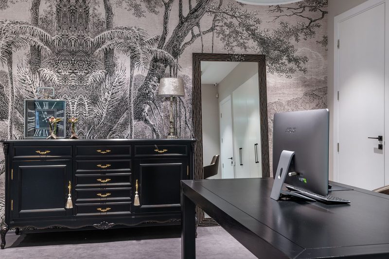 Home office with a black-and-white scenic mural of trees and wildlife, a black chest of drawers, standing mirror and desk